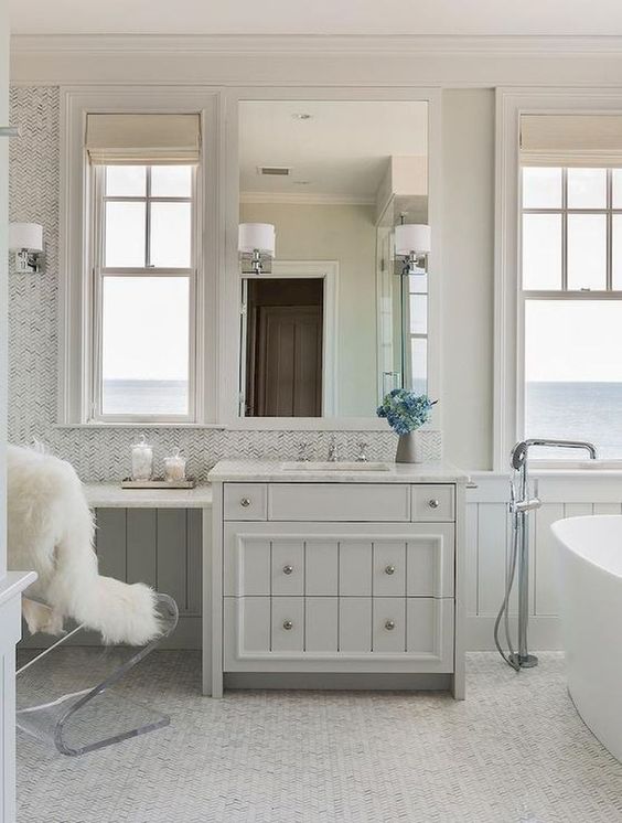 a contemporary tub, windows with sea views and a vintage meets contemporary vanity plus an acrylic chair