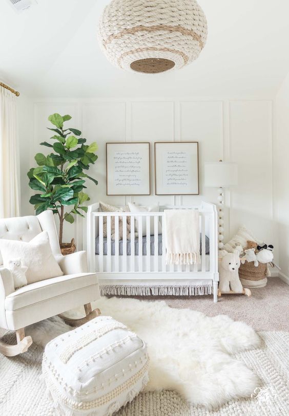a heavenly creamy nursery with a wicker lamp, a faux fur rug, a rocker, a white crib and a knit rug plus a Moroccan pouf