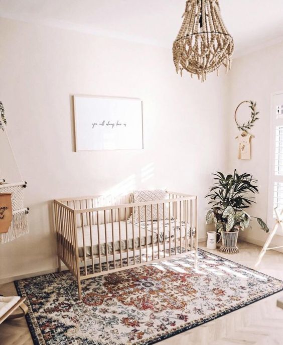 a light-filled boho nursery with a bead chandelier, a boho rug, potted greenery and a minimal artwork