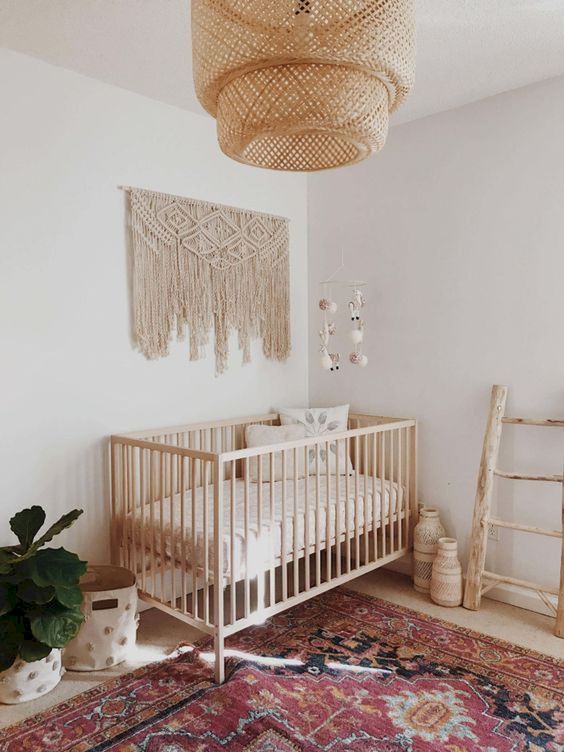 a minimal boho nursery with a large macrame, a wicker lamp, a boho rug, some vases and baskets for storage