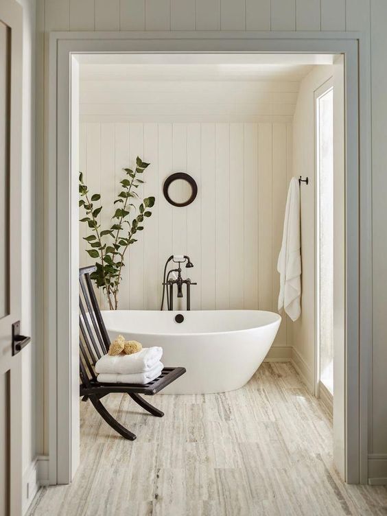 a neutral and warm-colored bathroom with shiplap, wood inspired tiles and a contemporary tub and black touches