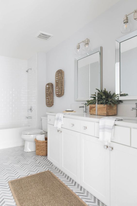 a transitional white bathroom is softened with decorative trays, a planter with greenery, a jute rug and a basket for storage