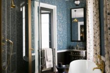 a vitnage-inspired bathroom with printed curtains, a chic black tub, gilded touches and blue printed wallpaper