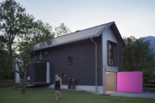 01 This holiday home is small and tall, with black exterior walls and a bright pink garage door