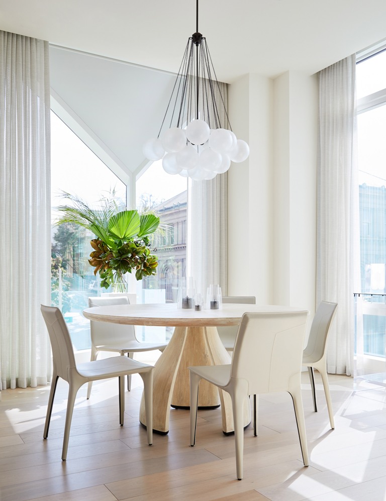 The dining space is done with a round table and curvy chairs plus a cluster of pendant lamps