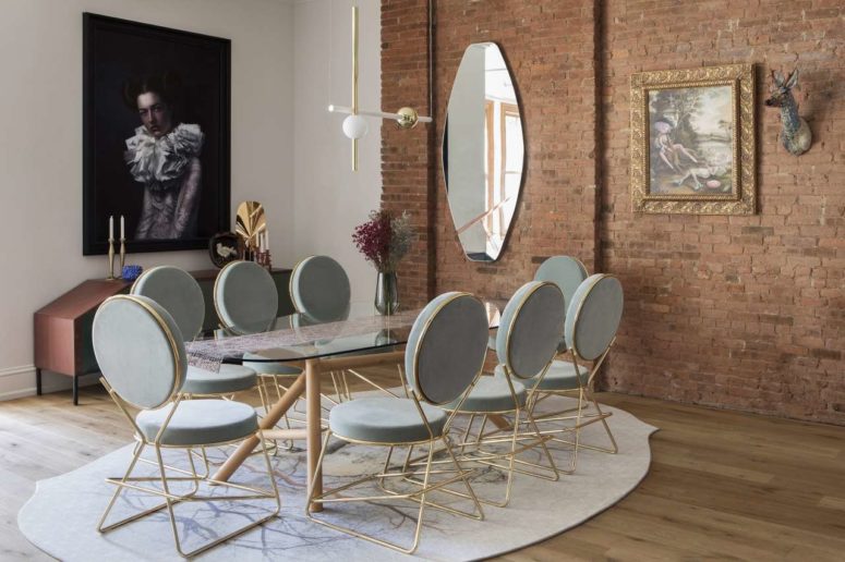 The dining space is done with chic grey and gold chairs and a glass table