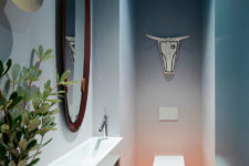 04 The powder room features gradient walls and a statement mirror and an artwork