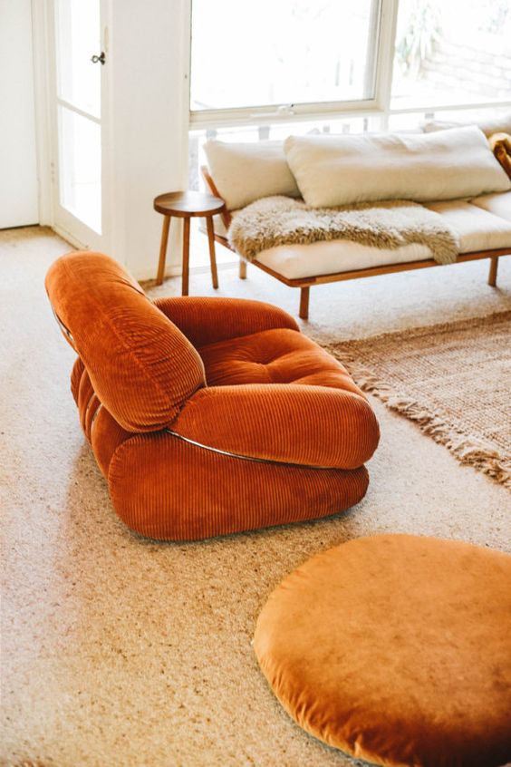A chic rust colored velvet chair is a stylish addiotion to a neutral and muted boho living room