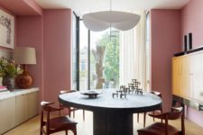 05 A dining room with a statement wooden dining table and a gorgeous chandelier features also pink walls