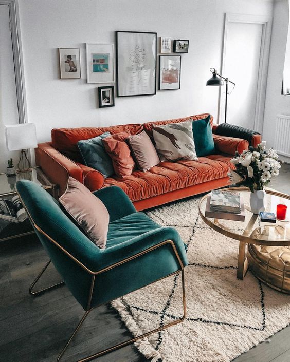 a rust-colored velvet sofa with muted and teal pillows plus a teal velvet chair for a bold fall setup