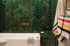 05 a statement green tile wall with a herringbone pattern and an additional green touch over the bathtub