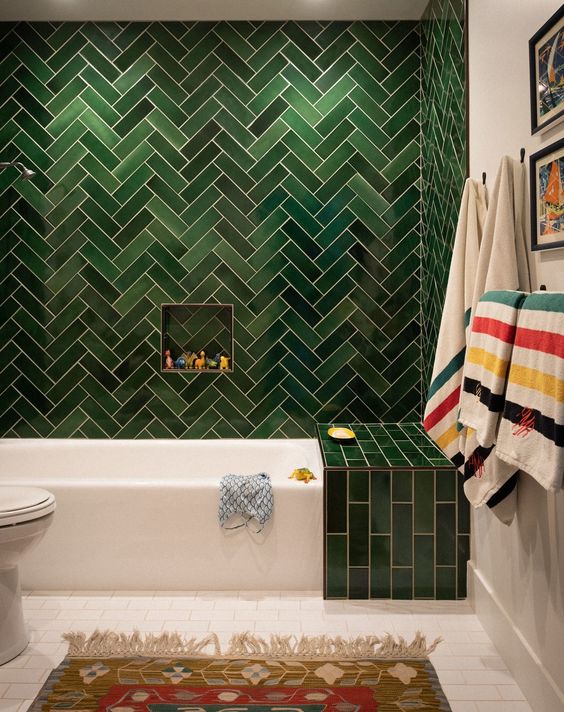 a statement green tile wall with a herringbone pattern and an additional green touch over the bathtub