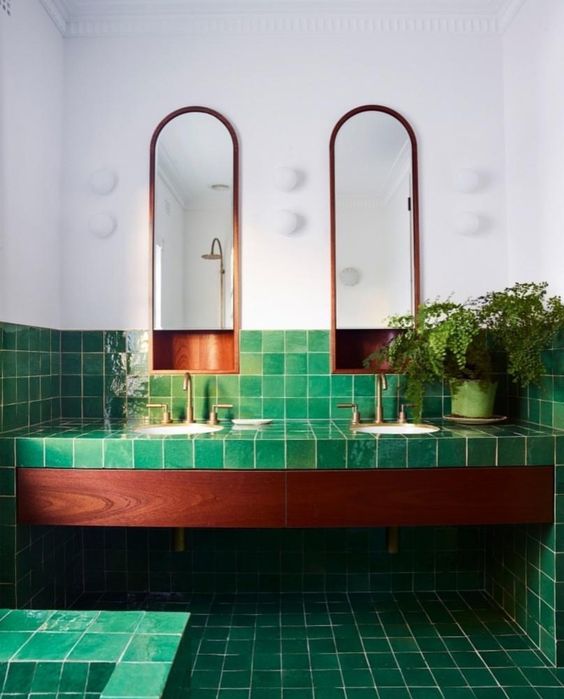 green tiles all over the bathroom contrast the rich stain of the wood and copper touches