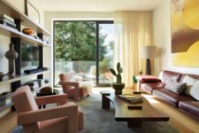 07 The living room is bright and bold, with pink chairs and a leather sofa plus an entrance to the terrace