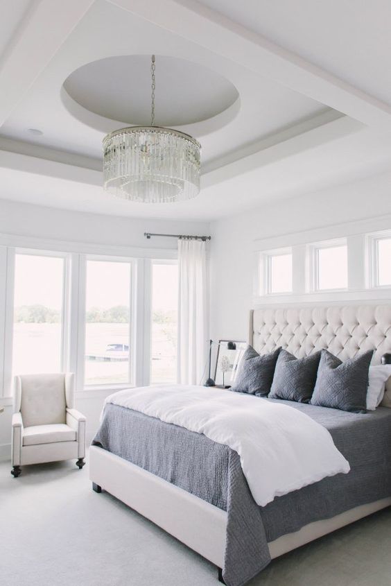 a creamy tufted headboard and a crystal chandelier are glam and cool accents for the space