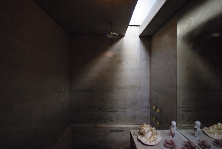 The bathroom is private and is made of concrete, with a skylight and some seashells for decor