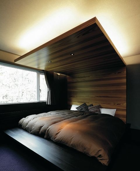 a gorgeous wooden headboard extended up to the ceiling features lights and creates a cozy sleeping alcove