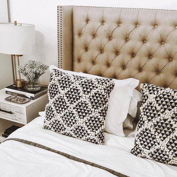 a neutral tufted wingback headboard with decorative nail trim is a chic and timeless idea that never goes out of style