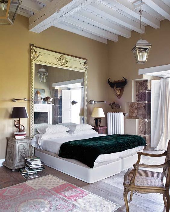 a statement mirror in a vintage frame is a unique headboard idea for a beautiful bedroom