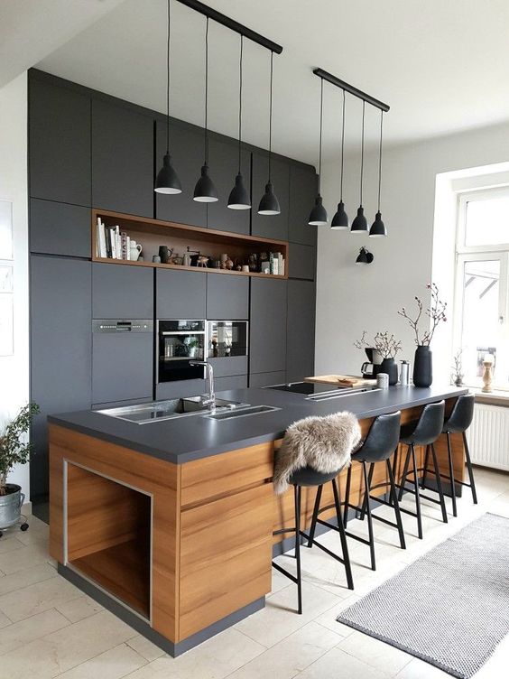 a super chic dark kitchen with matching blakc pendant lamps hanging in a row is a cool and bold idea