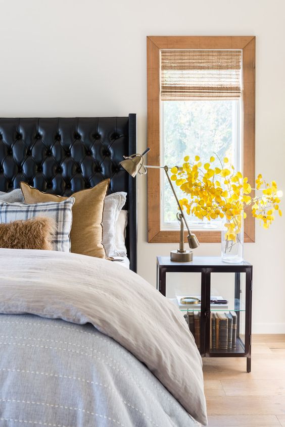 a black leather wingback tufted headboard and a dark stained nightstand add drama to the neutral bedroom