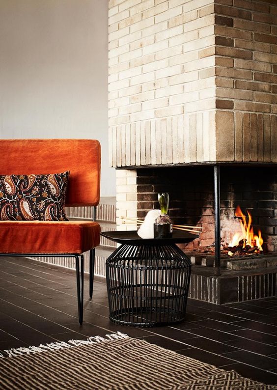 A bold orange velvet chair with hairpin legs brings mid century modern chic and a fall touch to the space