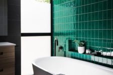 09 a contemporary bathroom done with a statement wall of emerald tiles and calm grey tiles on the rest of the surfaces