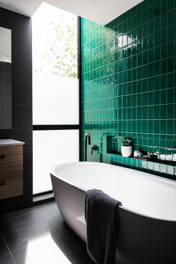 a contemporary bathroom done with a statement wall of emerald tiles and calm grey tiles on the rest of the surfaces