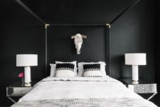 09 a gorgeous bedroom with black walls, a framed bed, mirror nightstands and a skull on the wall