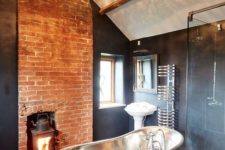 09 a stunning contrasting bathroom with a statement crystal chandelier, a metal tub and a brick wall with a hearth