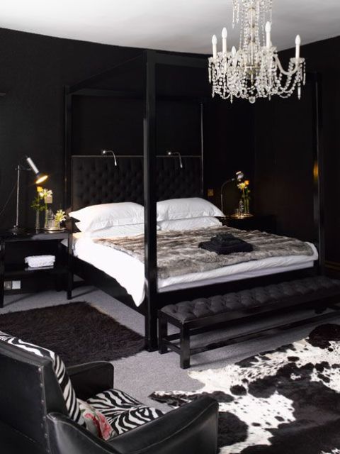 a luxurious bedroom with black walls, a crystal chnadelier, animal prints and some lights over the bed