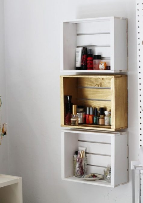 a trio of crate shelves on the wall in different colors to organize small stuff in your bathroom