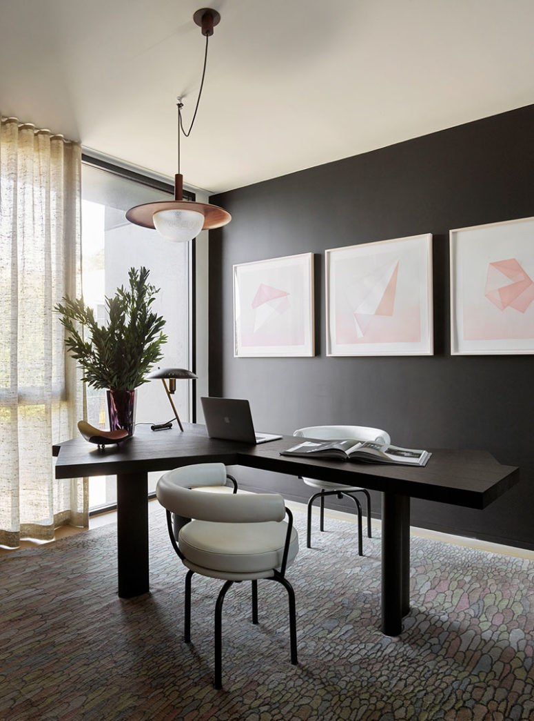 The home office nook is moody and is refreshed with pink artworks