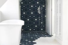 13 a laconic bathroom done with white tiles and navy hexagon tiles with stars that come under the tub
