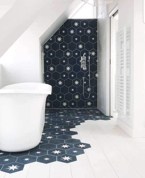 a laconic bathroom done with white tiles and navy hexagon tiles with stars that come under the tub