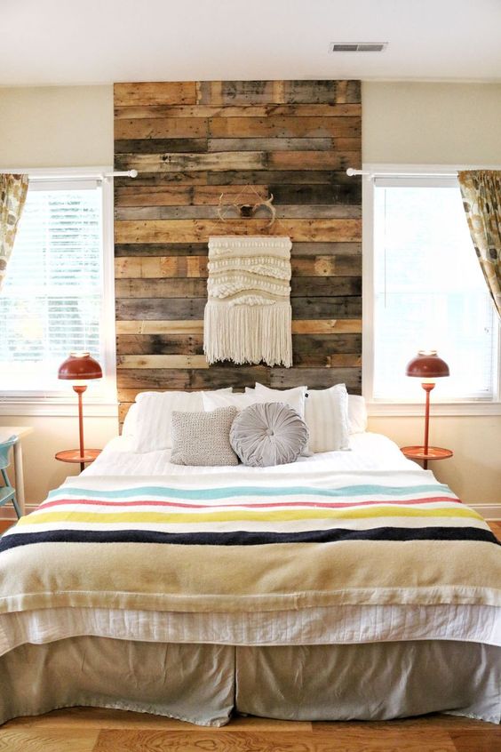 a reclaimed wood headboard coming up to the ceiling is accented with a macrame hanging and antlers for a boho feel
