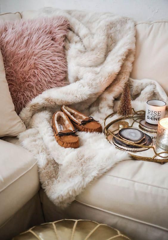 a pink faux fur pillow and a neutral fur blanket are amazign to cozy up in the fall