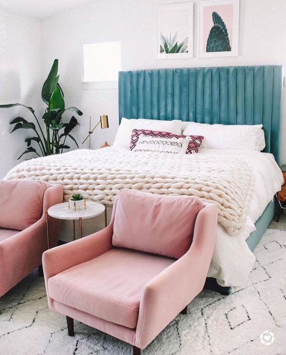 a beautiful blue upholstered headboard is soft and chic, and light pink chairs continue the pastel tone of the space