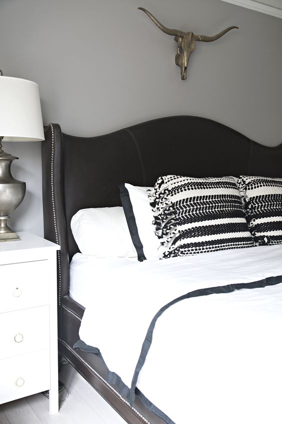 a black curved wingback headboard with decorative nail trim is a chic vintage-inspired idea
