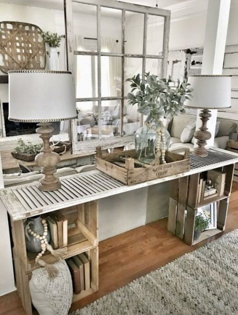a farmhouse console table made of wooden crates and a shutter looks very rustic and relaxed