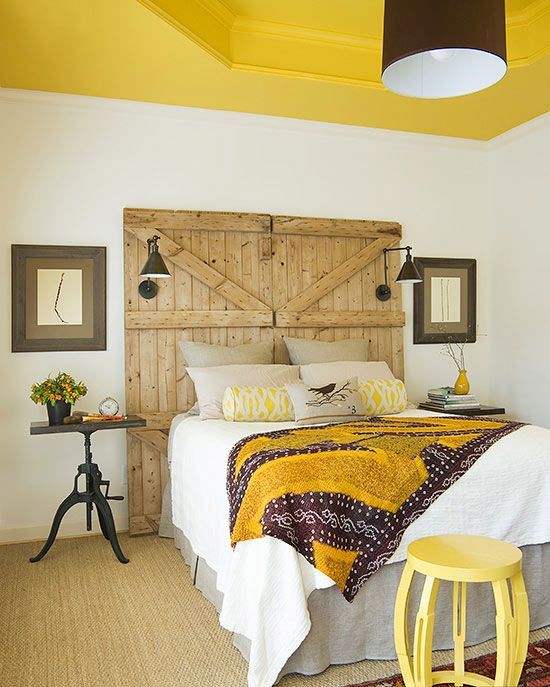 a barn door used as a headboard in this bright bedroom features lamps and add a cozy rustic touch