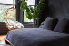 18 a welcoming bedroom with black walls, potted greenery, a black beddign set and a hanging chair