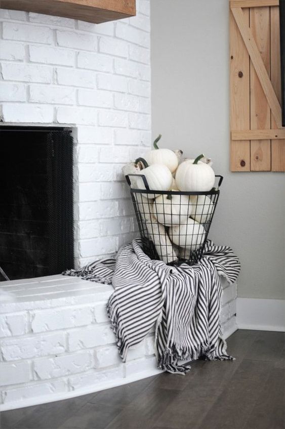 a wire basket filled with white pumpkins and with a black and white blanket will glam up your space