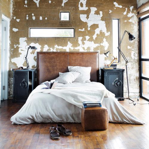 a brown leather sleek headboard and a matching square pouf are a base for an industrial bedroom