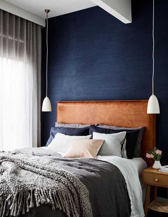 a brown leather upholstered headboard is a warming up touch to the welcoming bedroom done in grey and navy