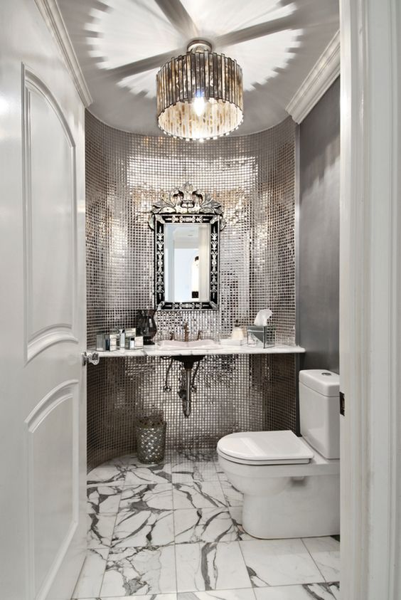 a glam mudroom with shiny reflective tiles, a marble floor and a refined frame mirror