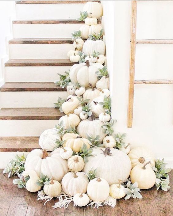 A staircase decorated with white pumpkins, gourds and pale greenery to make it fall like