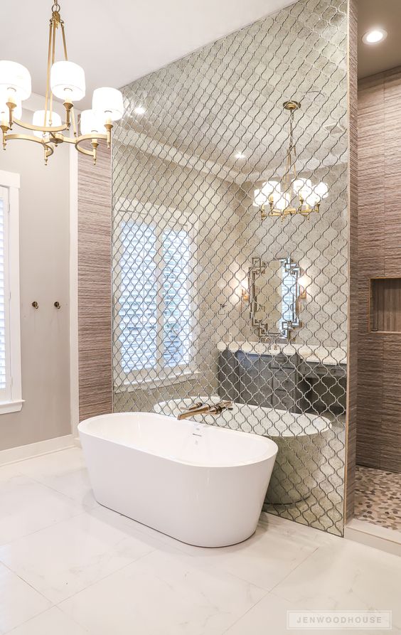 a wall done with reflective Moroccan tiles separates the bathtub from the rest of the space and accents it
