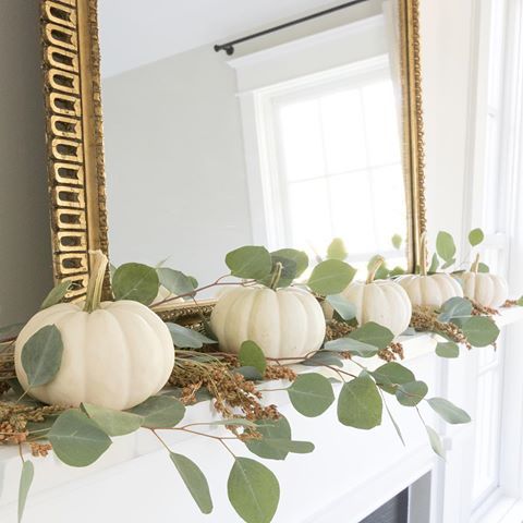 a fall mantel dcorated with white pumpkins, eucalyptus and with a statement gold ramed mirror