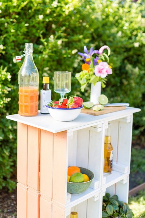 a pastel outdoor bar made of crates painted in pastel shades and with a wooden tabletop